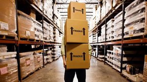 Image of a person carrying boxes in a warehouse poor inventory control can lead o retail business failures