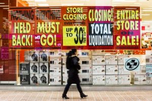 Woman walking by a store closure saleRetail store closures 2017