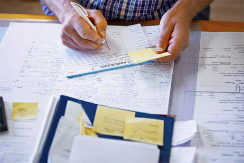 A man's hands holding a pen white writting on an invoice show retailers financial problems can add up